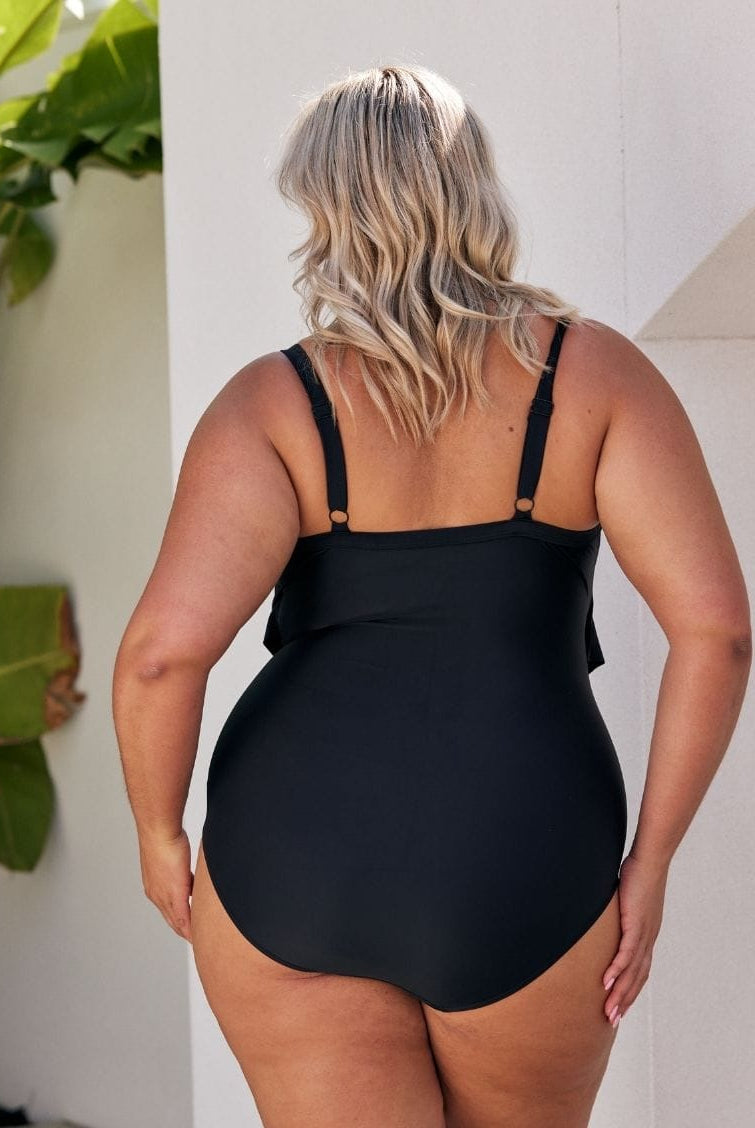 Woman wearing a black ruffled swimsuit by a pool