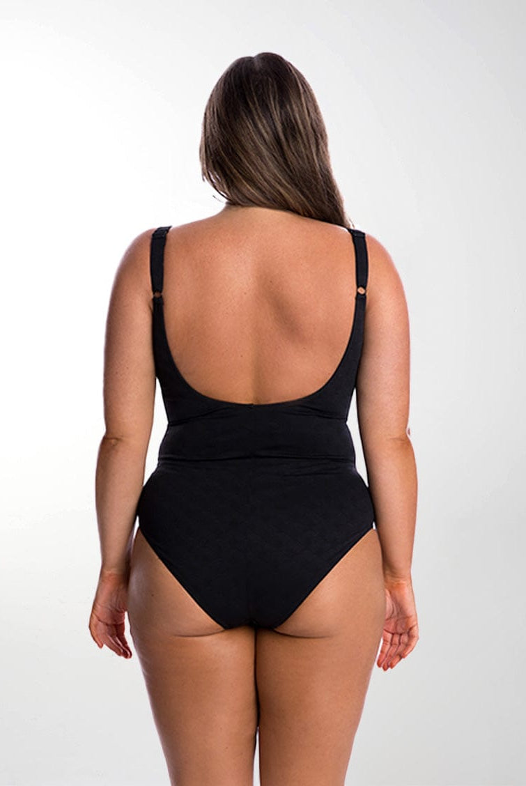 Back of model in studio wearing criss cross textured one piece with scoop back and adjustable straps