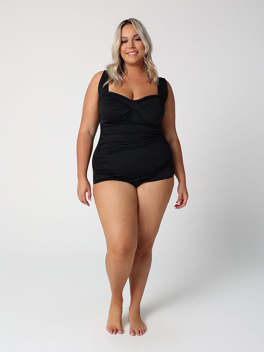 Woman wearing a black swimsuit against a white background