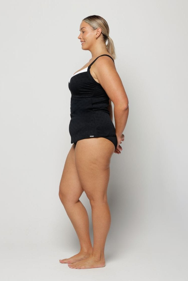 Woman wearing a black tank top and shorts on a white background