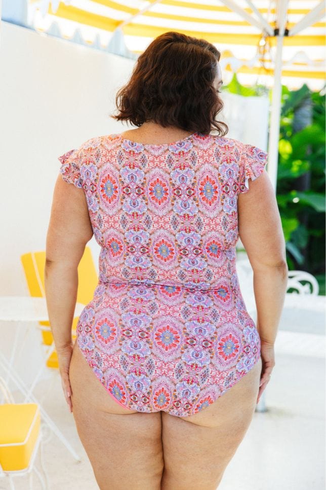 back of model wearing pink paisley high back one piece
