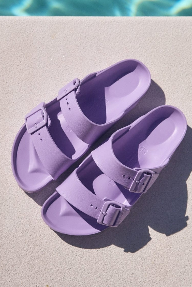 Pair of purple sandals on a diving board with water in the background