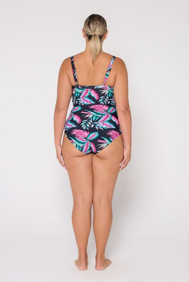 Woman wearing a tropical leaf patterned swimsuit on a white background