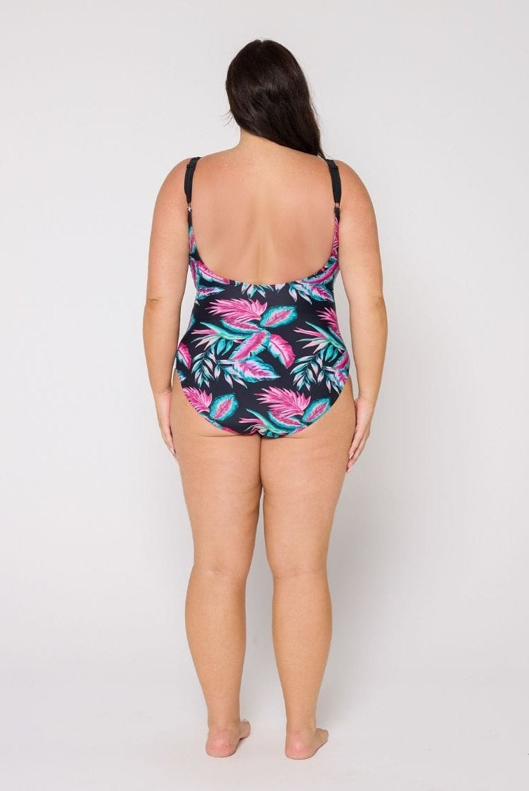 Woman wearing a tropical leaf patterned swimsuit on a white background