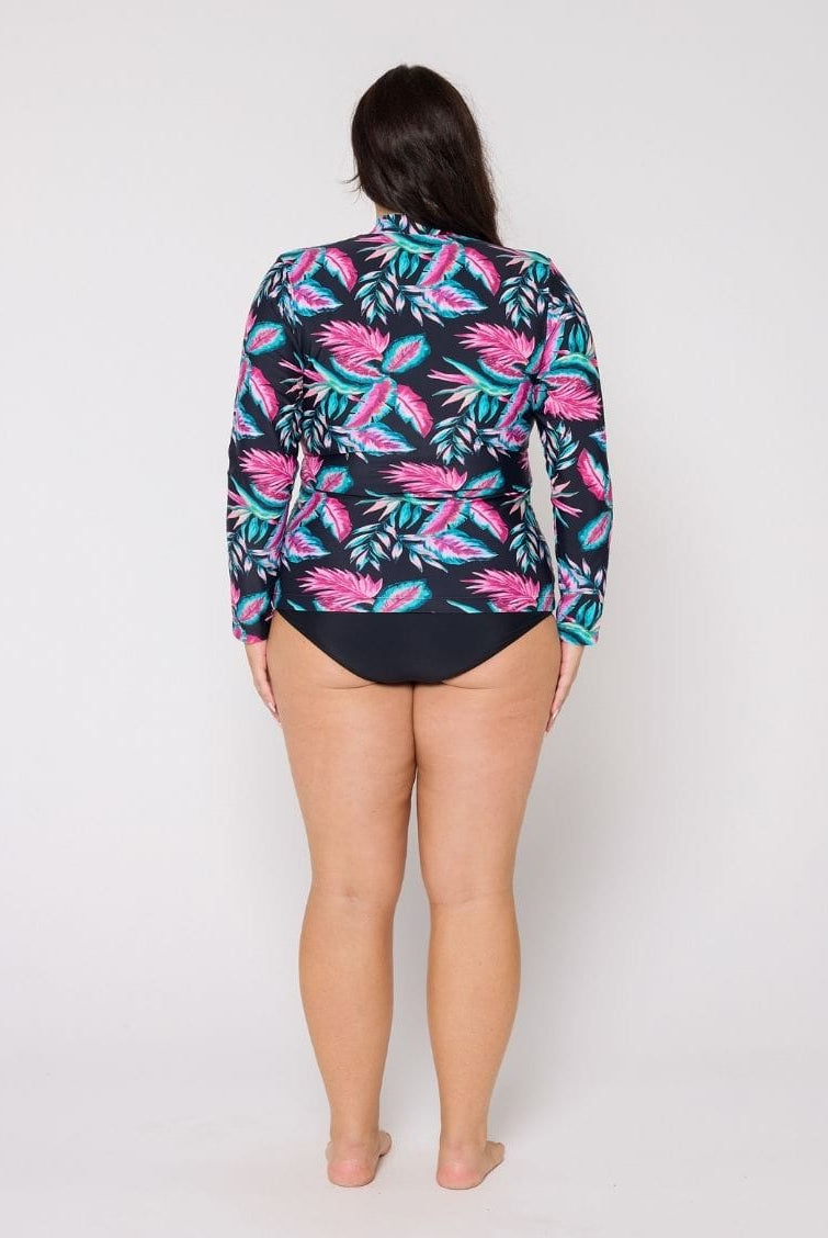 Woman wearing a colorful tropical print shirt over a swimsuit on a white background