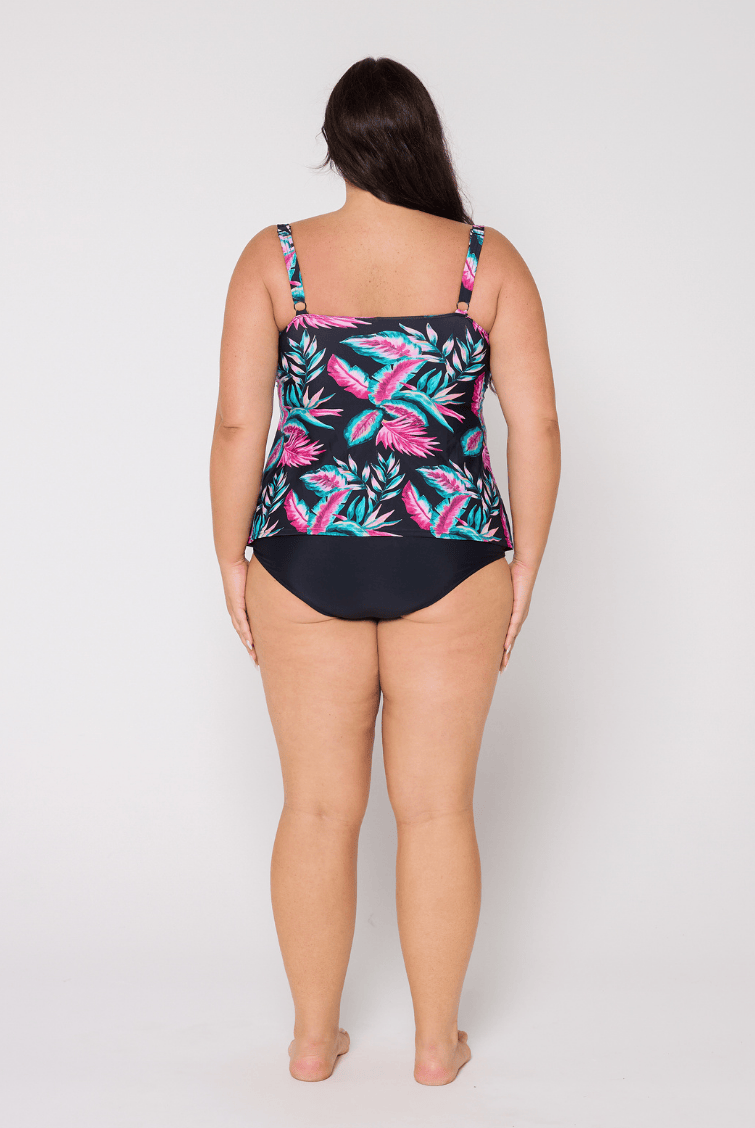 Woman wearing a swimsuit with a tropical leaf pattern on a plain background