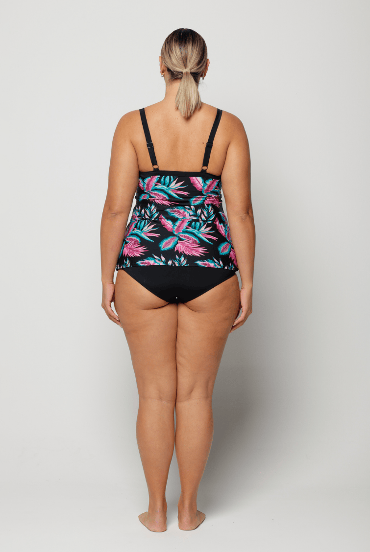 Woman wearing a black swimsuit with pink floral pattern on a white background