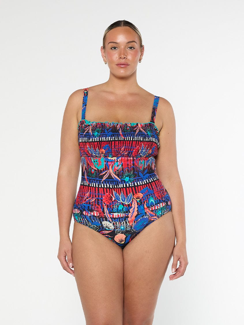 Blonde woman wearing a colorful patterned swimsuit in a studio with removable straps
