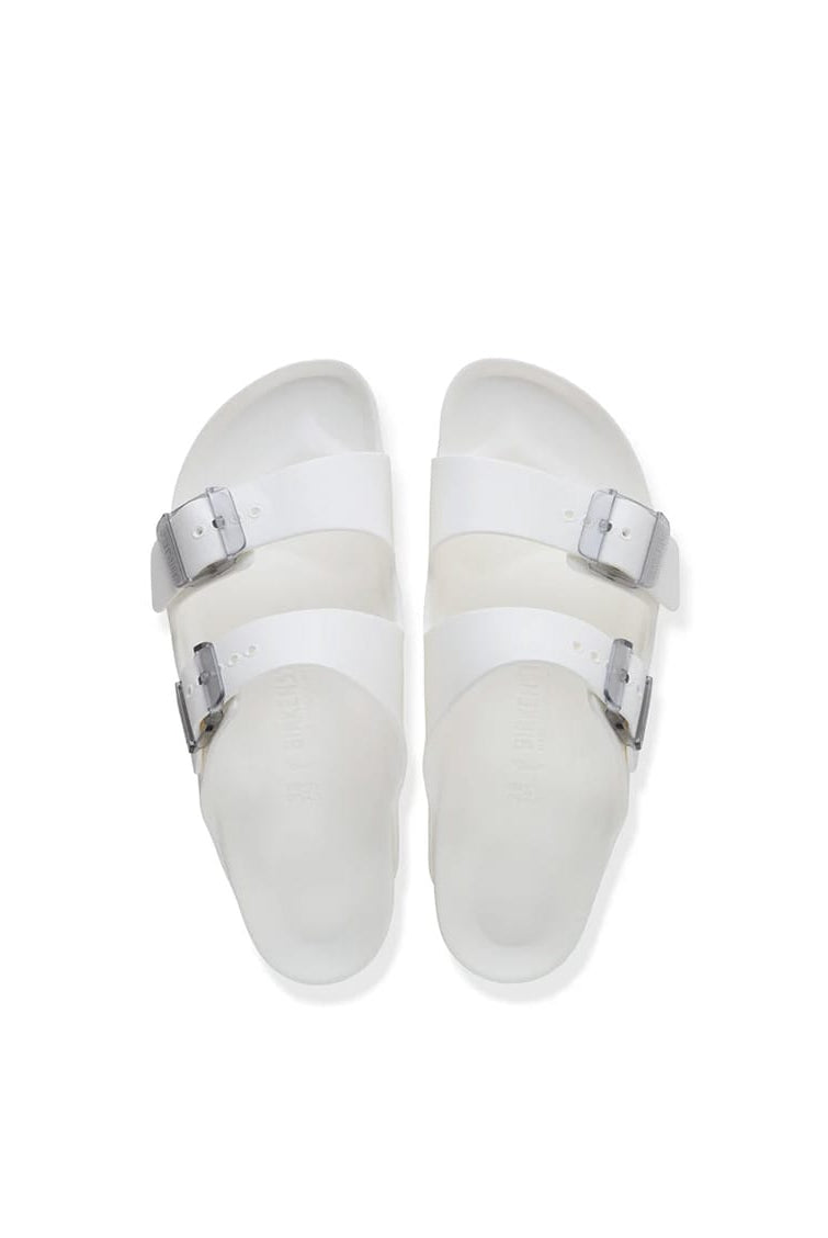 A pair of white double-strap slide sandals with silver buckle closures, photographed from a top-down perspective on a clean white background.
