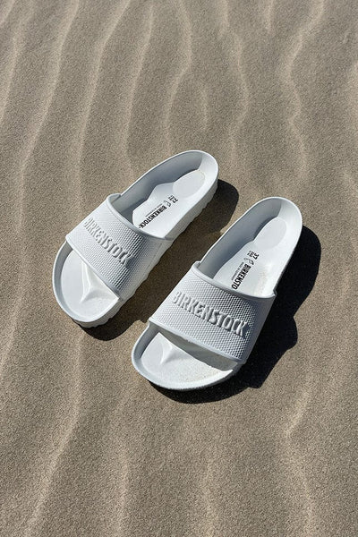 White birkenstock slip on sandals on the beach for curve women