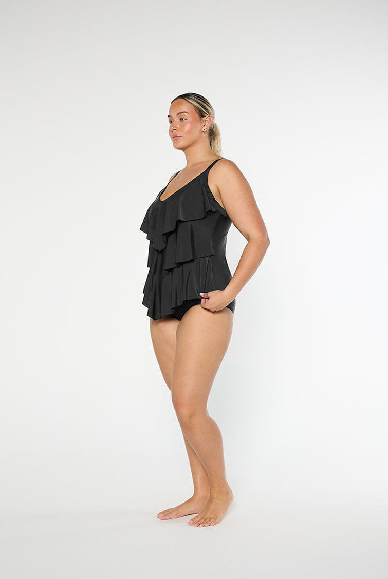 Woman wearing a black ruffled swimsuit on a white background