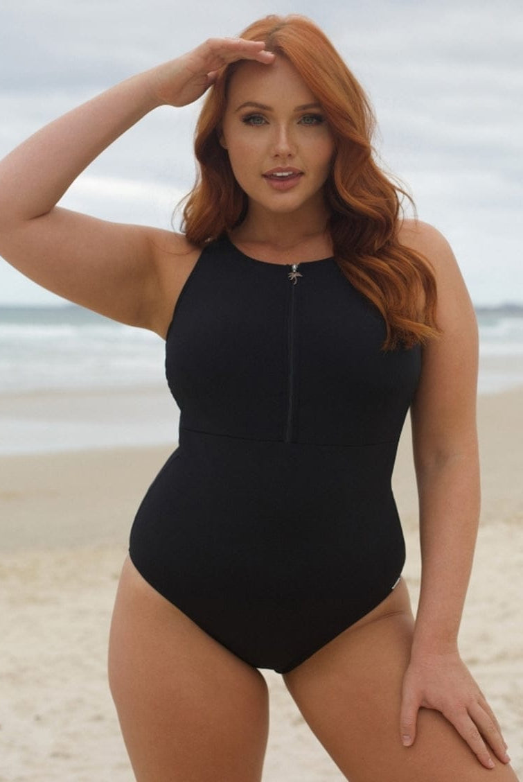 Woman in a black swimsuit standing on a beach
