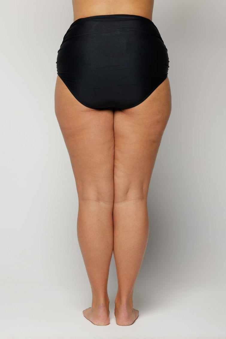 Person wearing black high-waisted underwear on a plain background