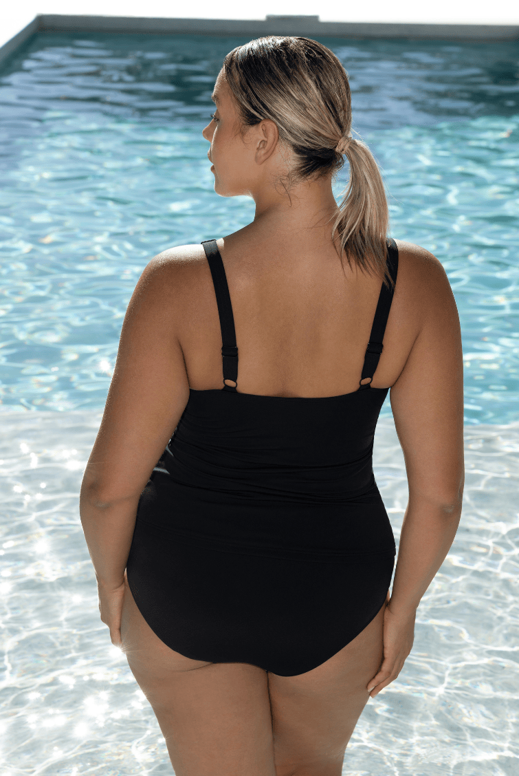 Woman standing in pool wearing a chlorine resistant tankin top with adjustable straps