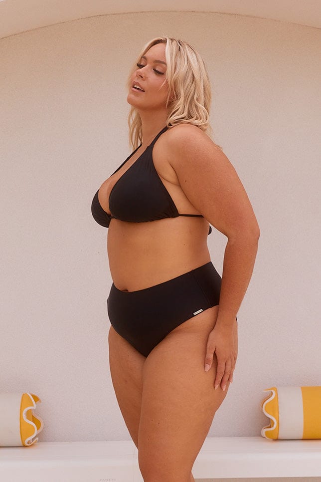 Blonde model showing side of black high rise bikini pant