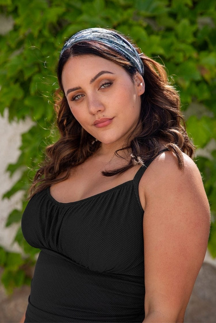 Woman wearing a black top with a green leafy background