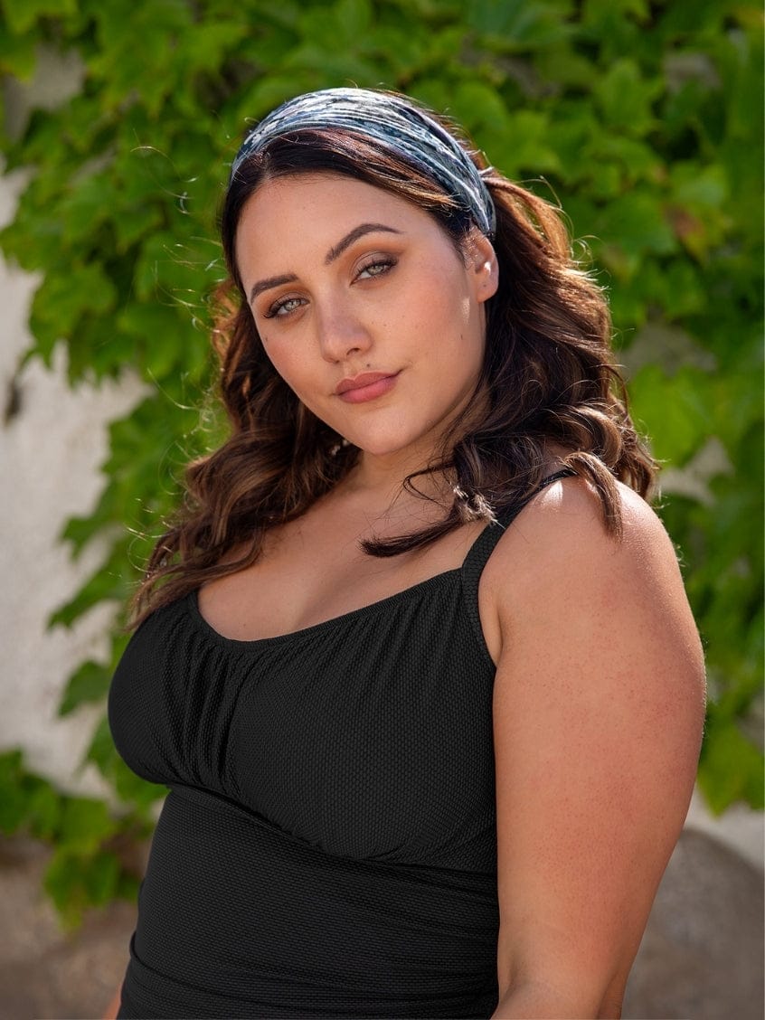 Woman wearing a black top with a green leafy background