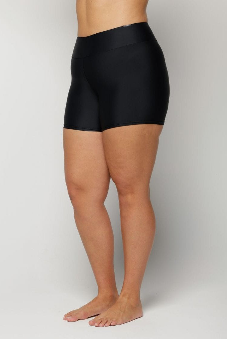 Woman wearing black high-waisted shorts on a plain background