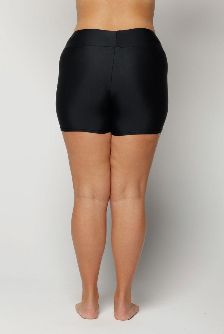 Woman wearing black high-waisted shorts on a plain background
