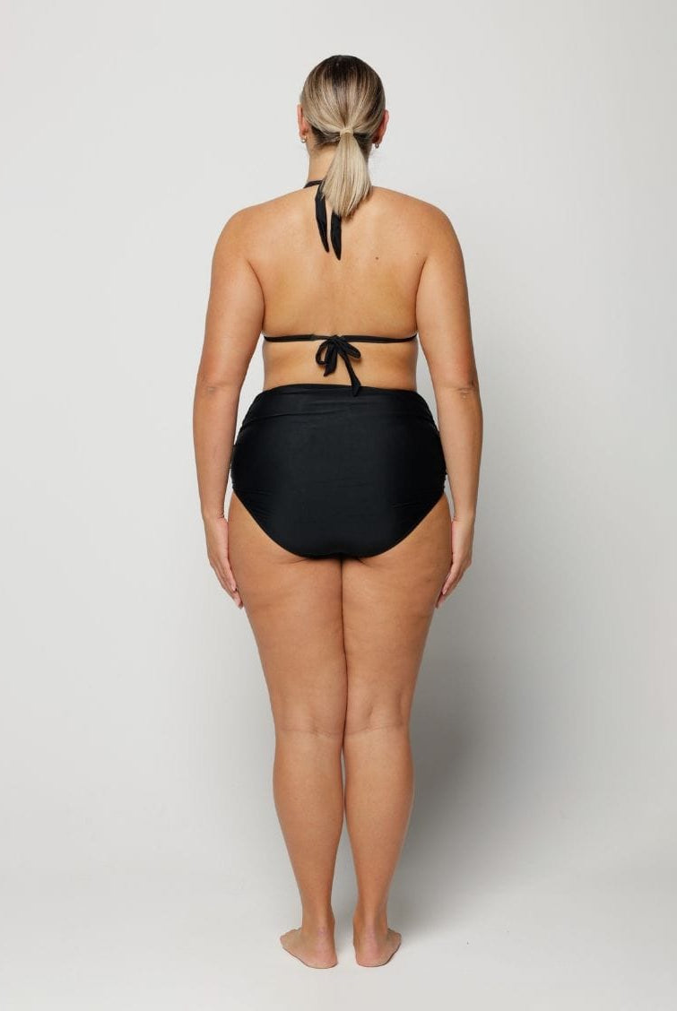 Woman wearing a black bikini on a plain background