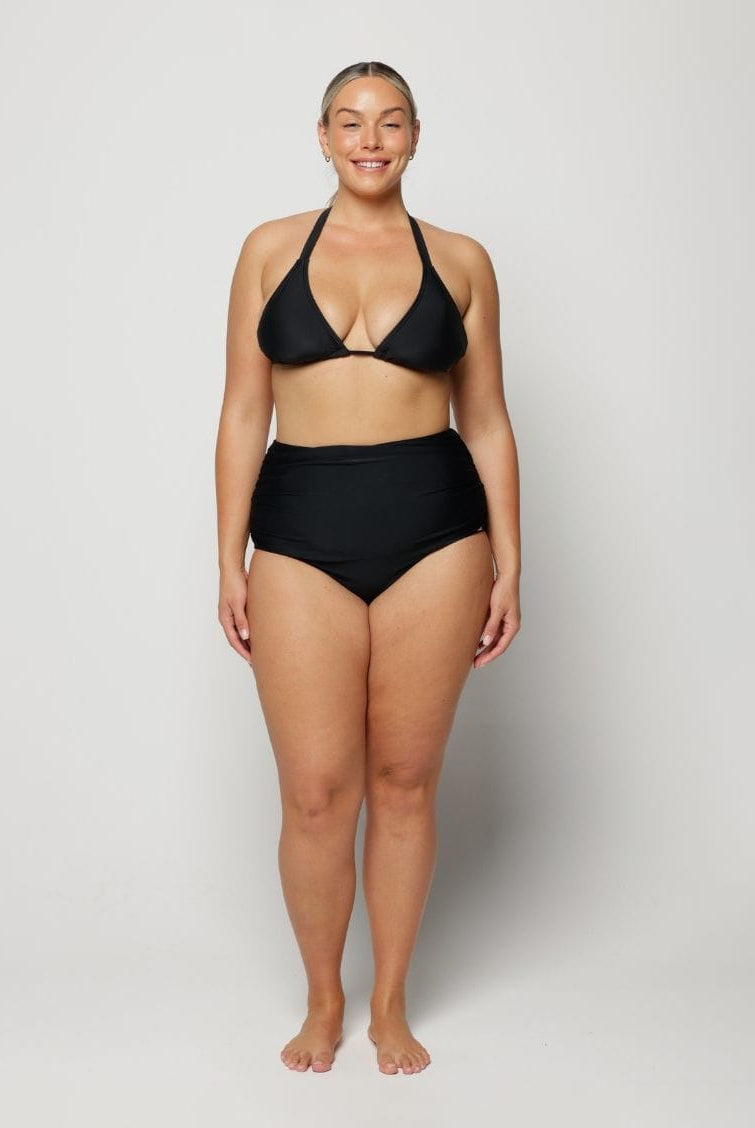Woman wearing a black bikini on a plain background