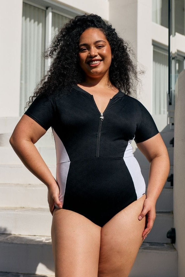 Model by pool wearing a zip front one piece with black and white panel detail