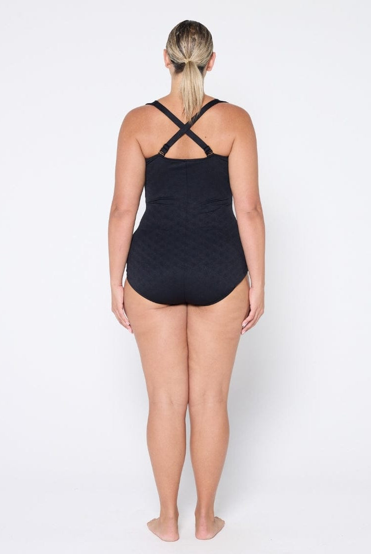 Person wearing a black swimsuit with criss-cross straps on a white background