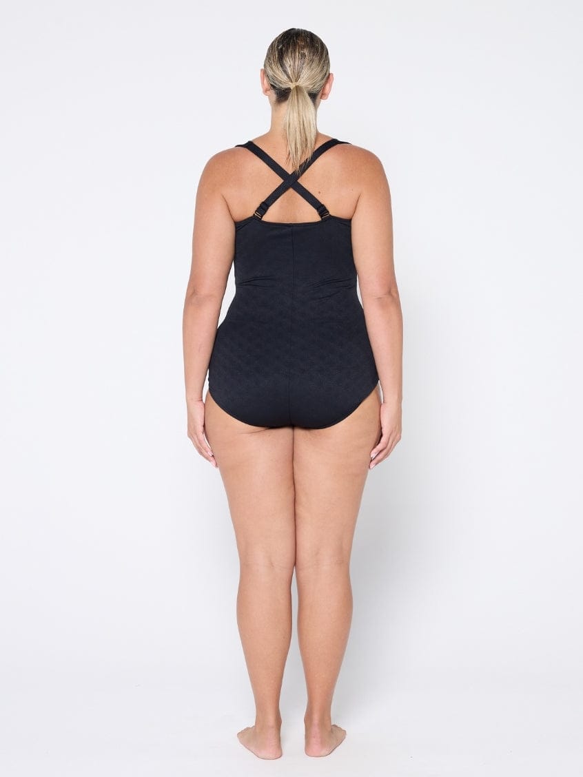 Person wearing a black swimsuit with criss-cross straps on a white background