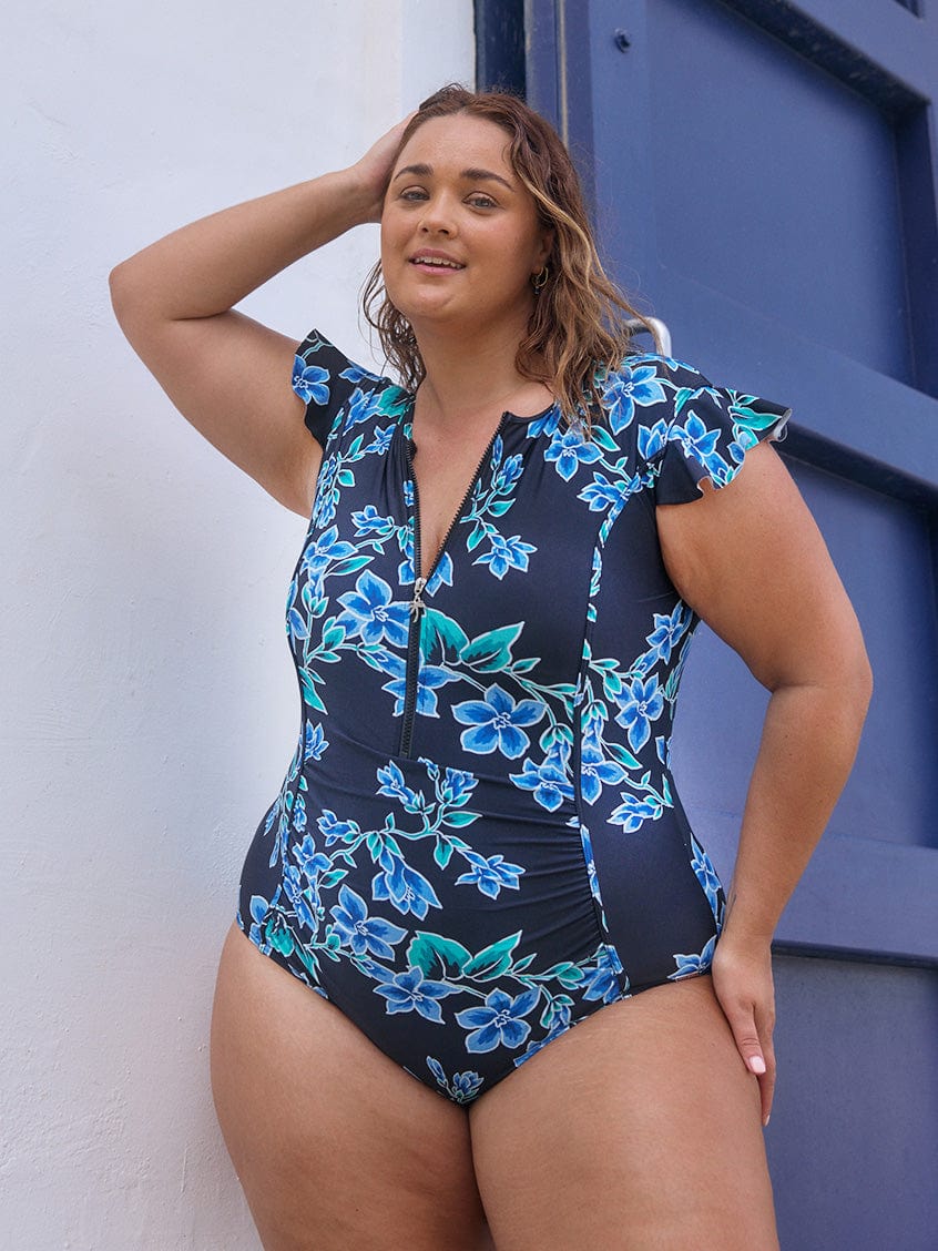 Brunette curve model wearing a frill sleeve one piece with zip front detail and ruching