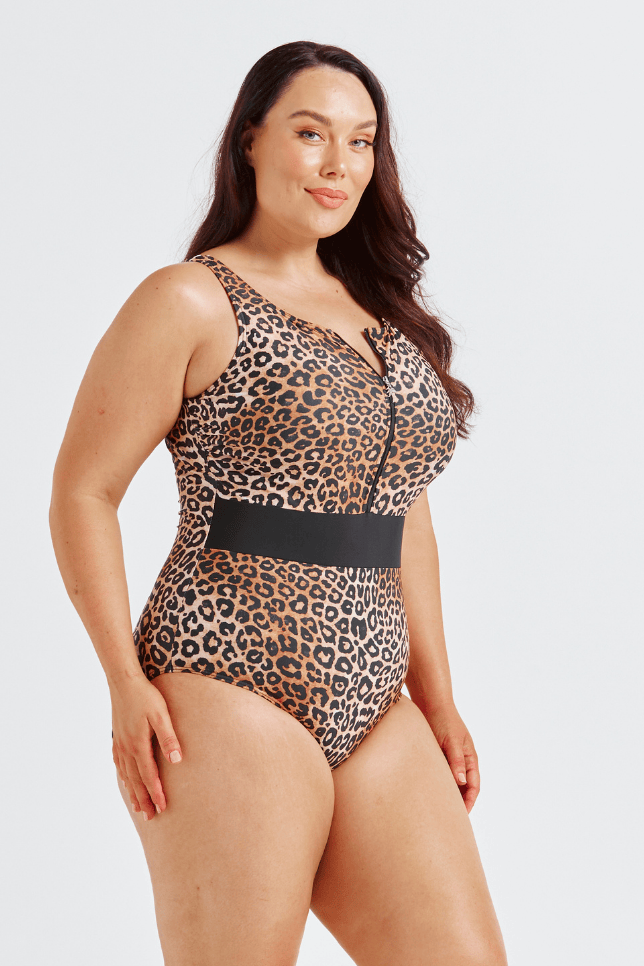 Woman wearing a leopard print swimsuit with a black belt on a white background