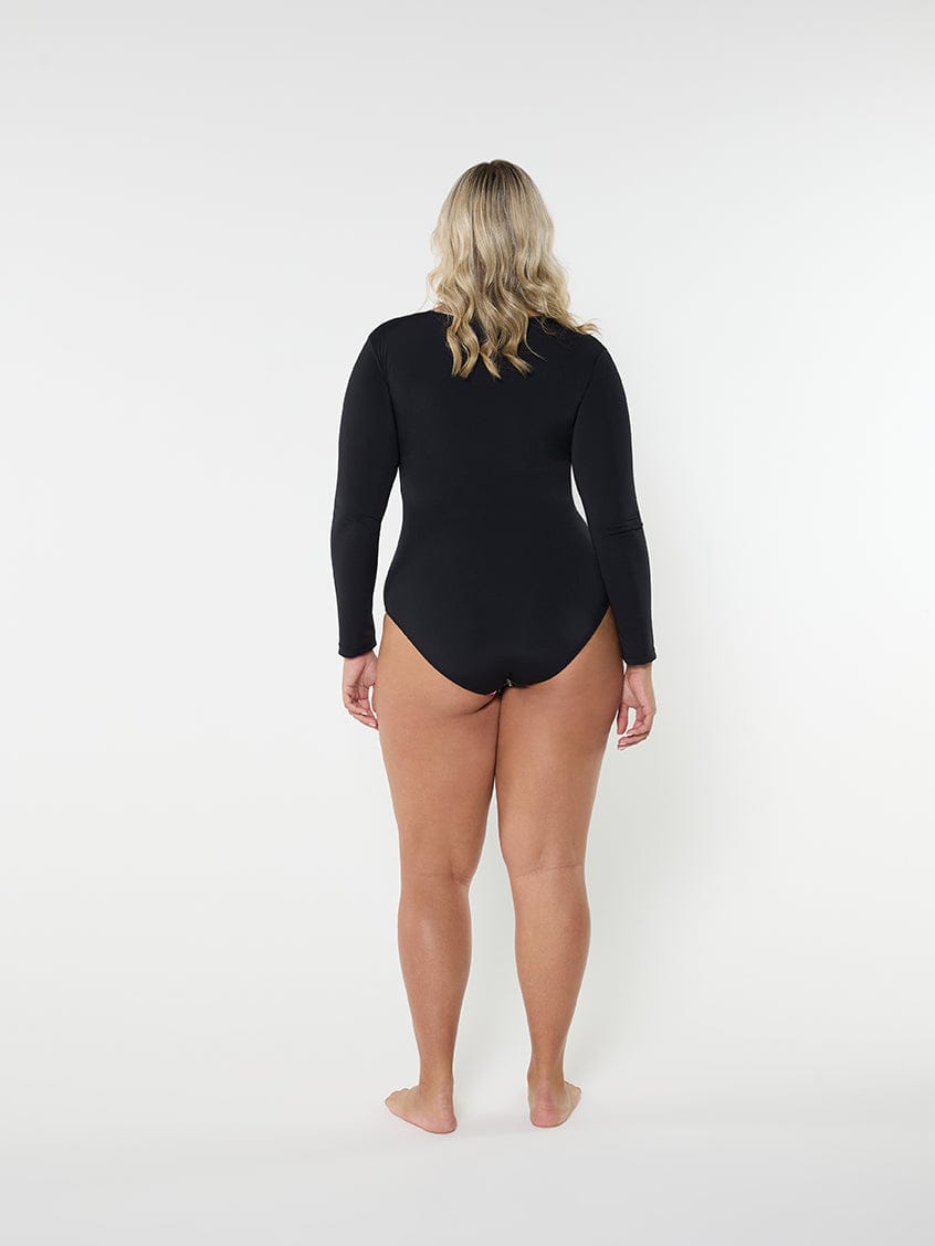 Person wearing a black swimsuit with long sleeves on a white background