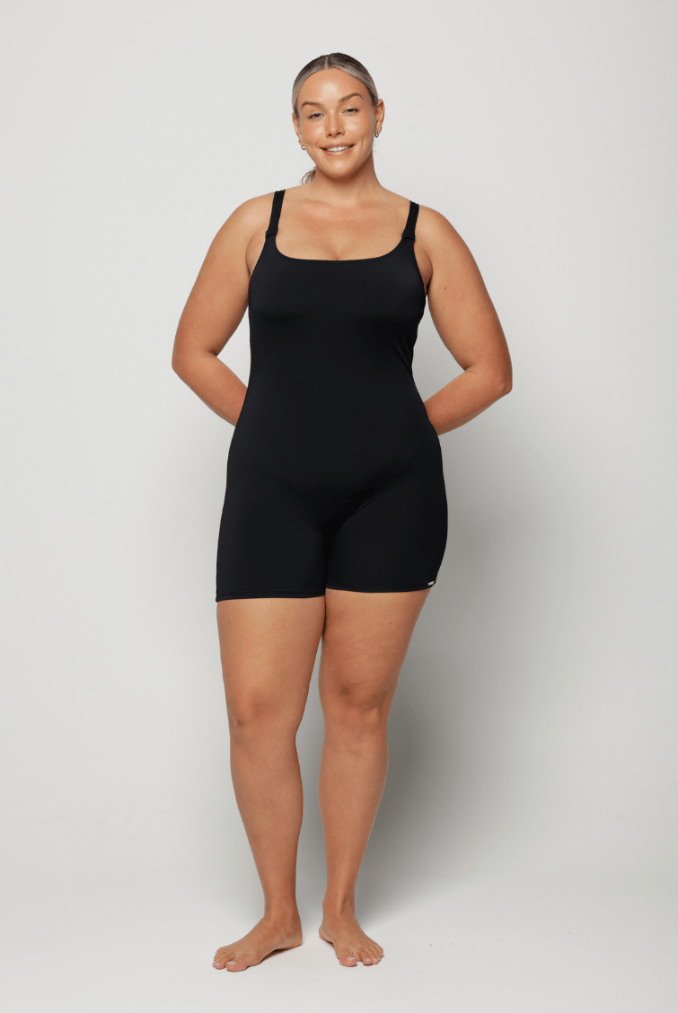 Person wearing a black boyleg one piece in chlorine resistant against a white background
