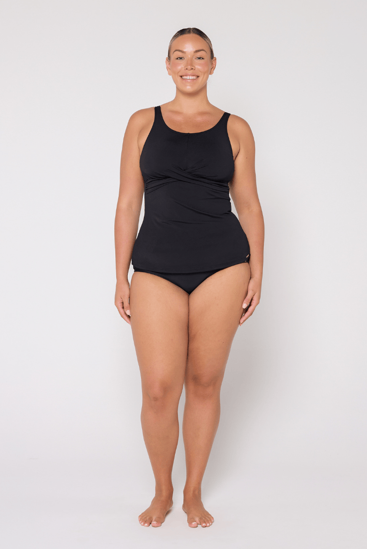 Woman standing in pool wearing a chlorine resistant tankin top with twist front detail