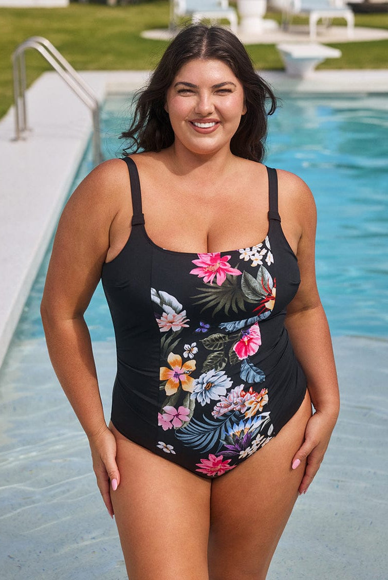 Woman wearing a black floral swimsuit by a pool