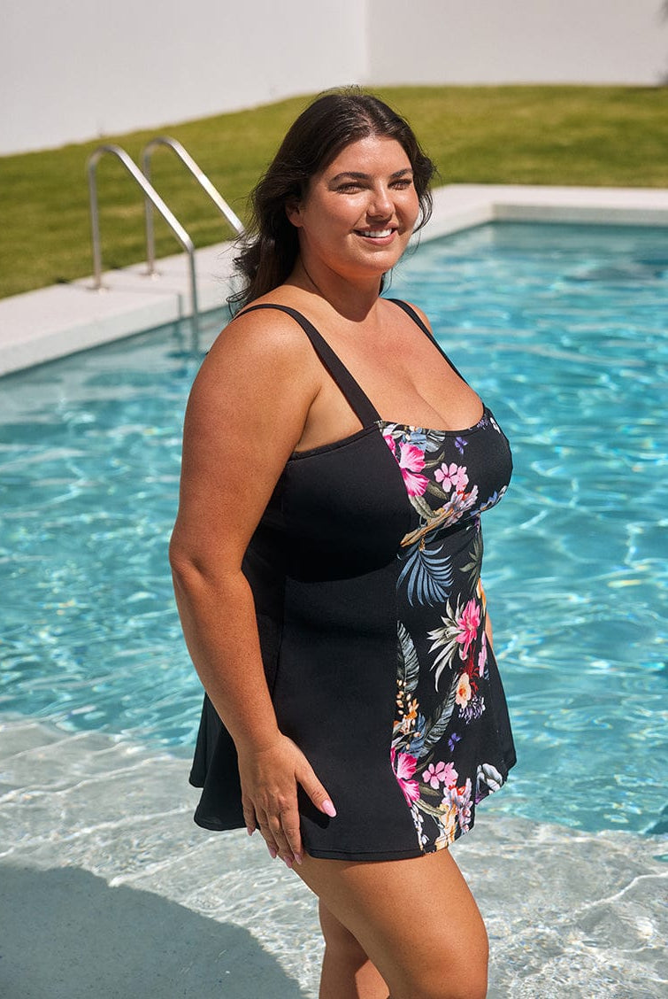 Woman in a black floral dress standing by a pool
