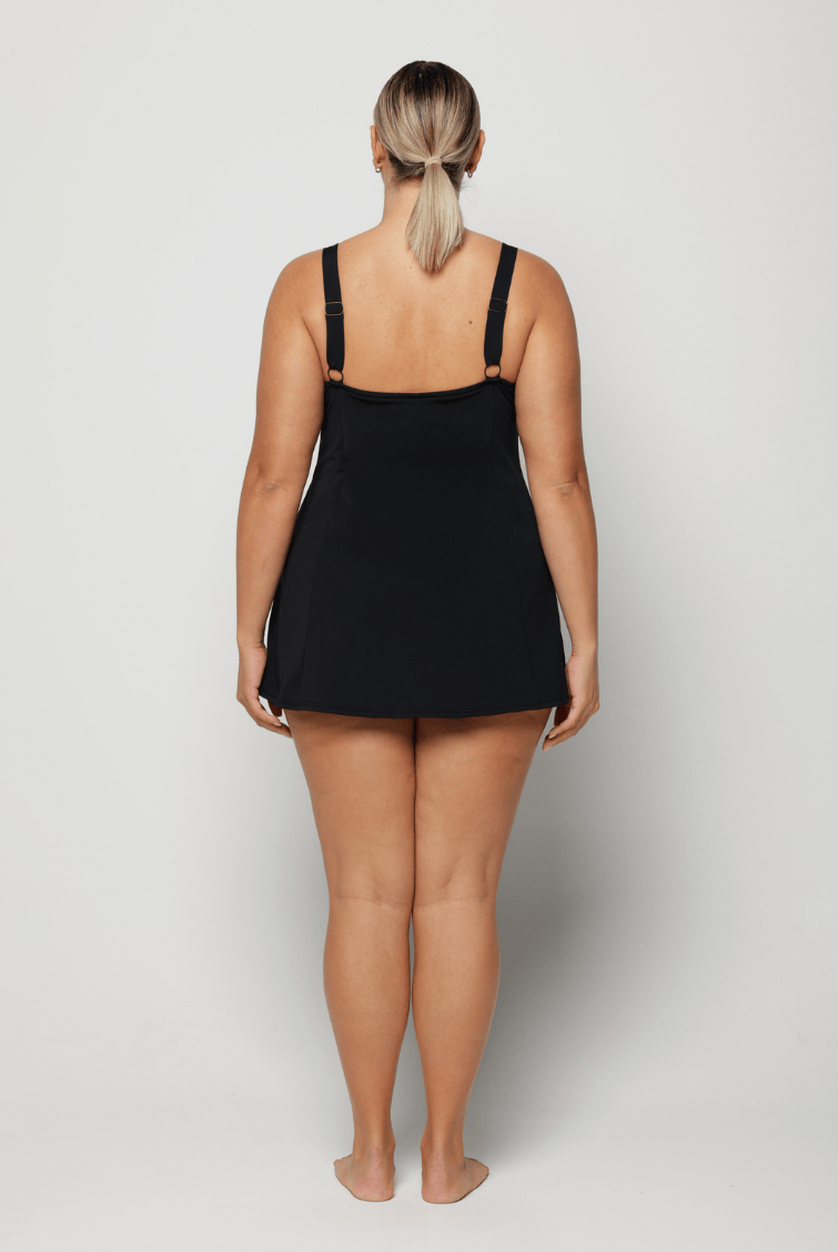 Person wearing a black and blue floral slip swim dress on a plain background