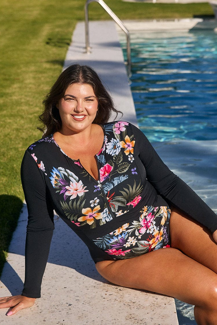 Woman in a floral swimsuit sitting by a pool