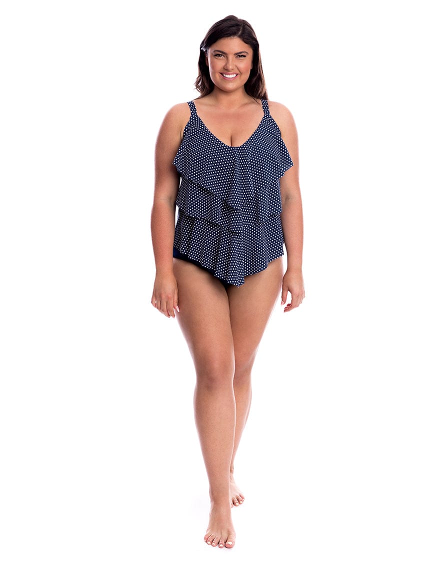 Woman wearing a navy blue polka dot swimsuit on a white background
