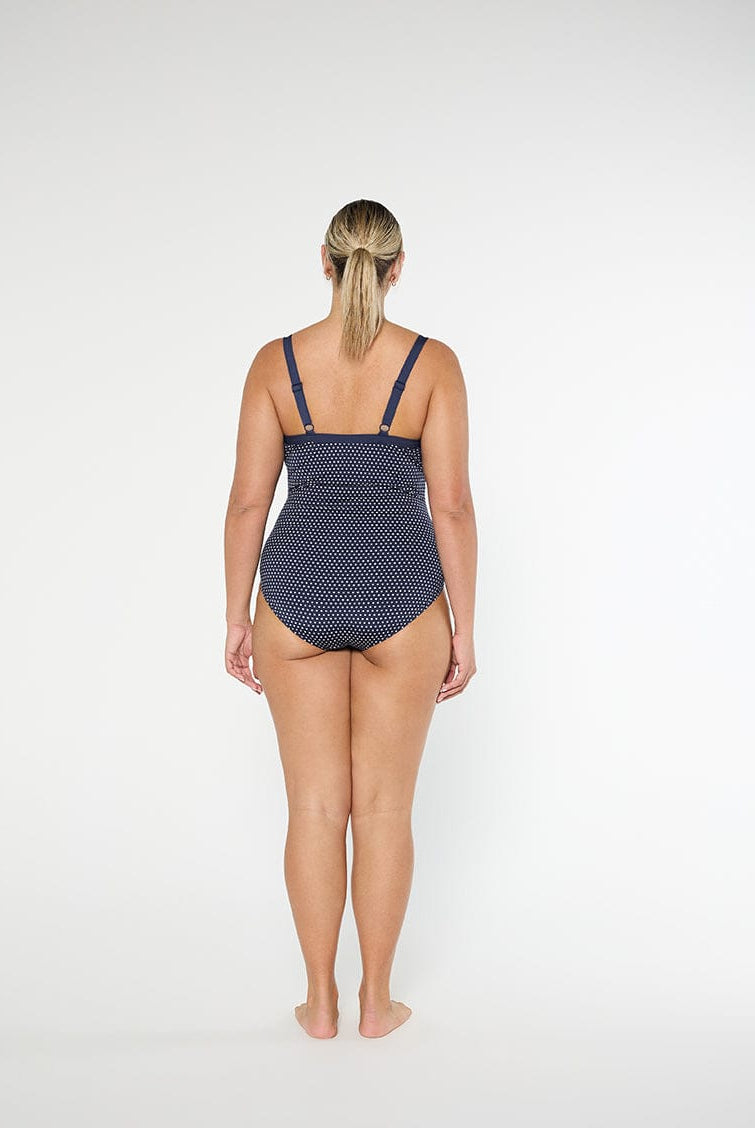 Woman wearing a navy patterned swimsuit on a white background