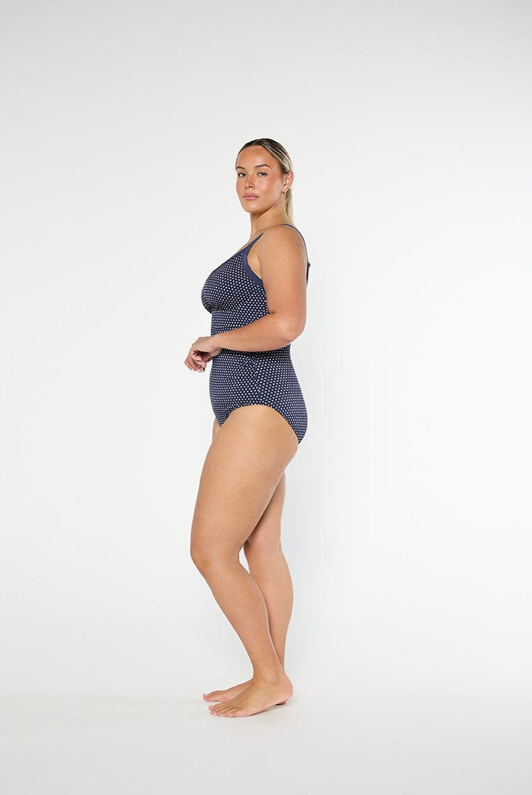 Woman wearing a navy polka dot swimsuit on a white background