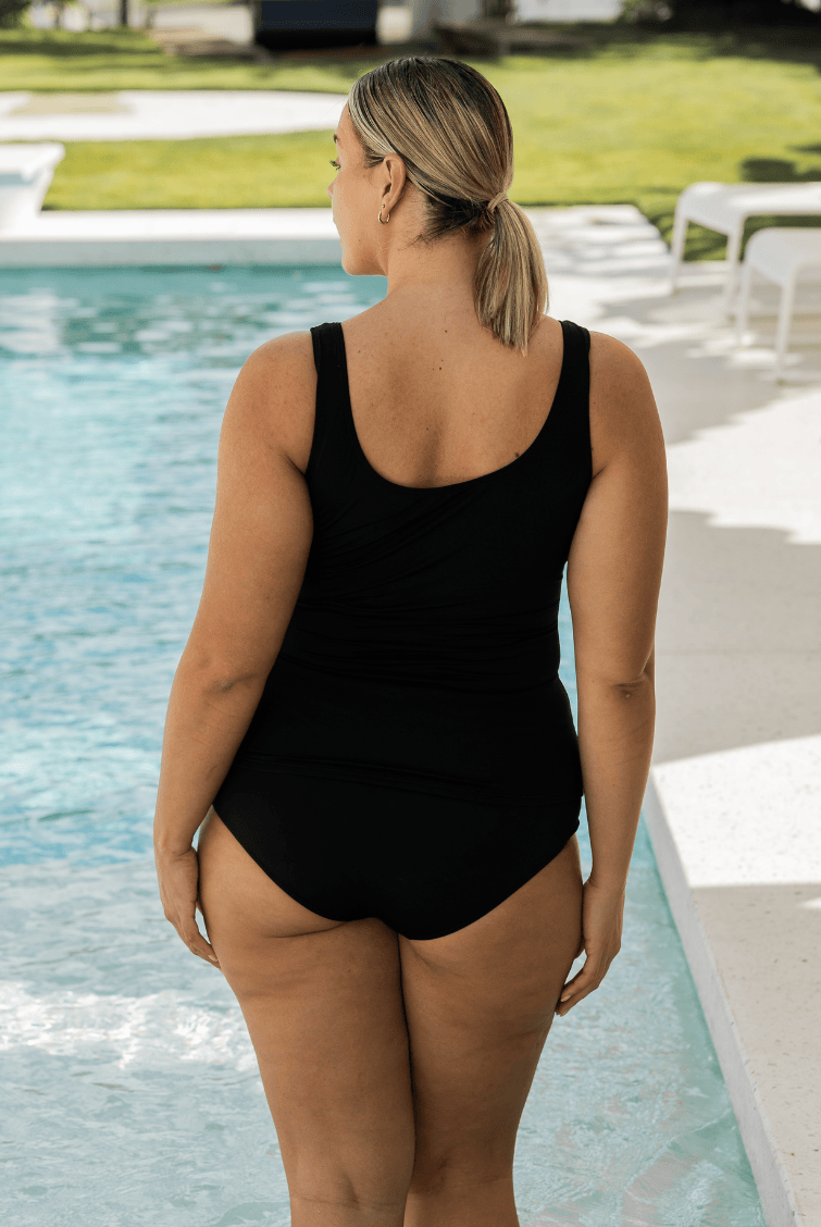 Back of model standing in pool wearing sleeveless one piece in chlorine resistant