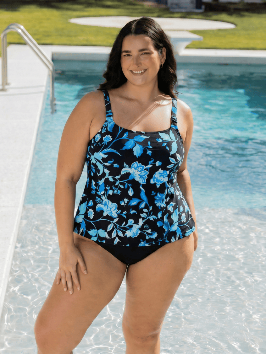 Woman wearing a black and blue floral swimsuit by a pool