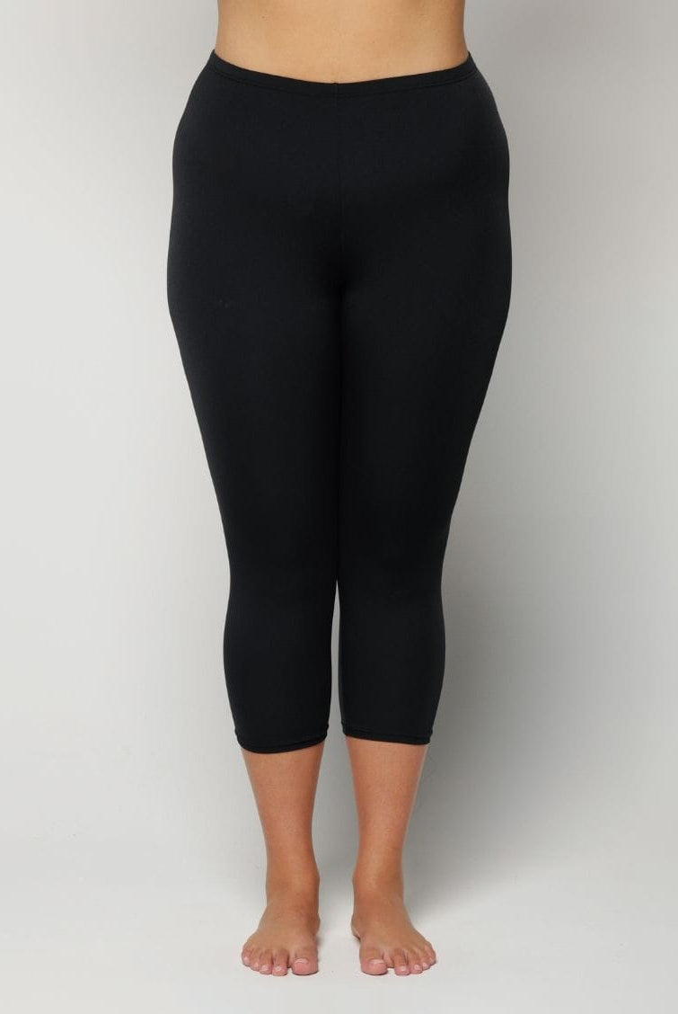 Woman wearing black capri leggings on a plain background
