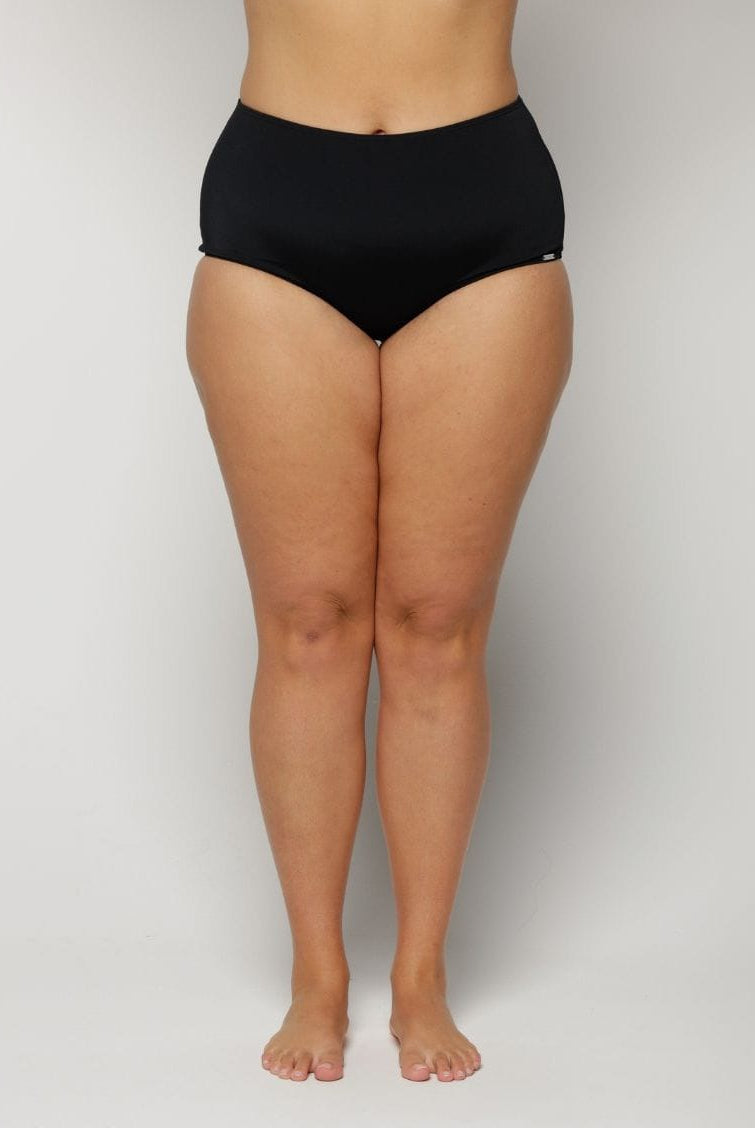 Woman wearing black high-waisted underwear on a plain background
