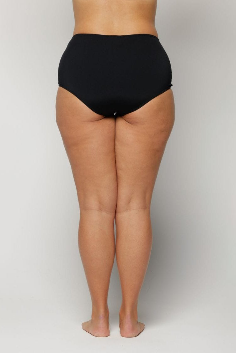 woman wearing black high-waisted underwear on a plain background