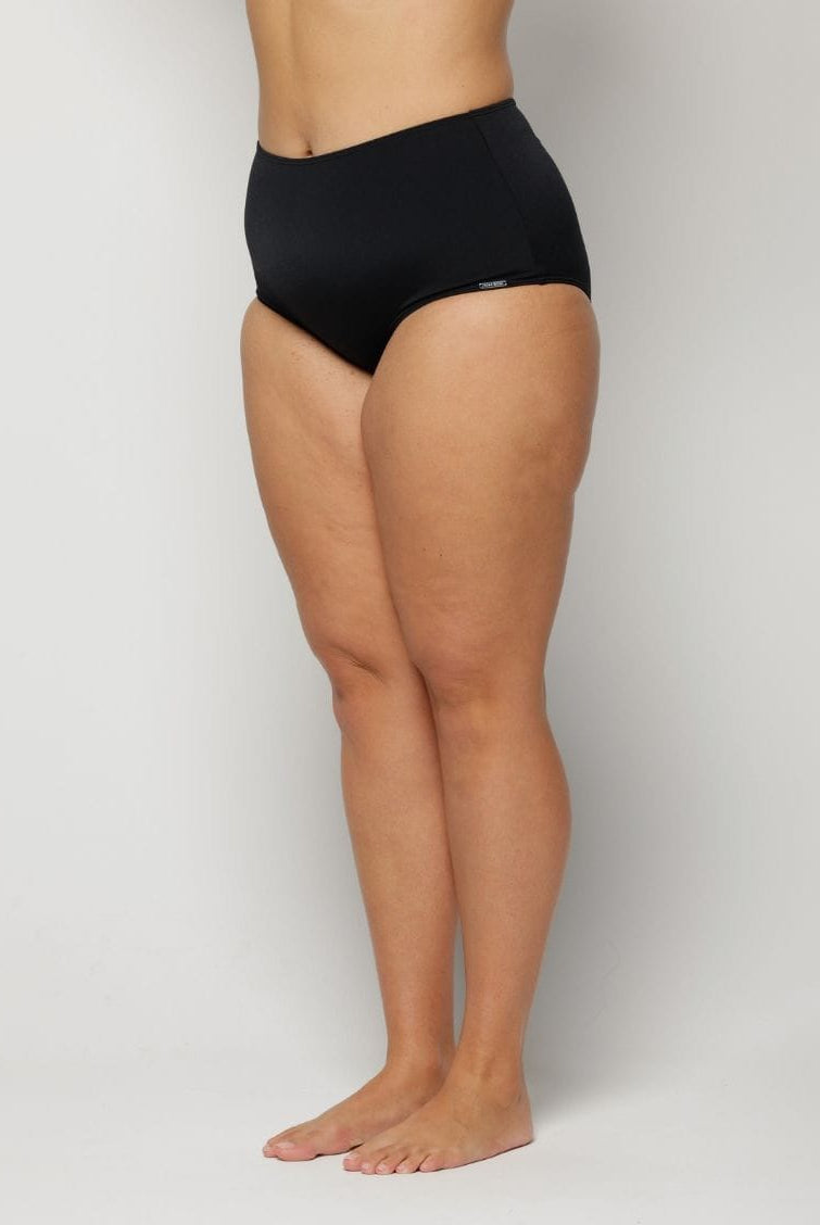 Woman wearing black high-waisted underwear on a plain background