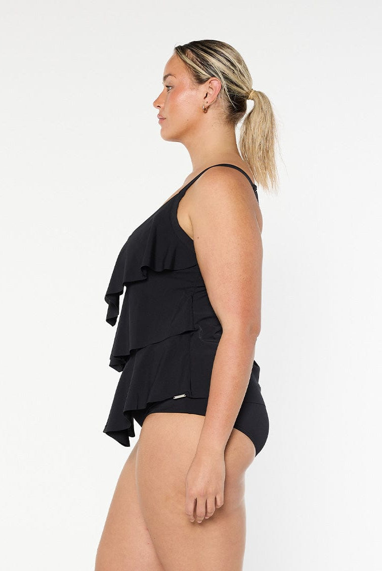 Plus size model wears ruffle tankini top in black chlorine resistant fabric