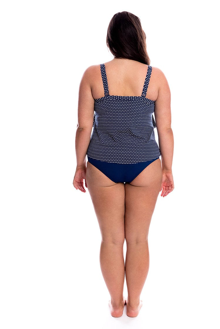 Woman wearing a navy polka dot swimsuit on a white background