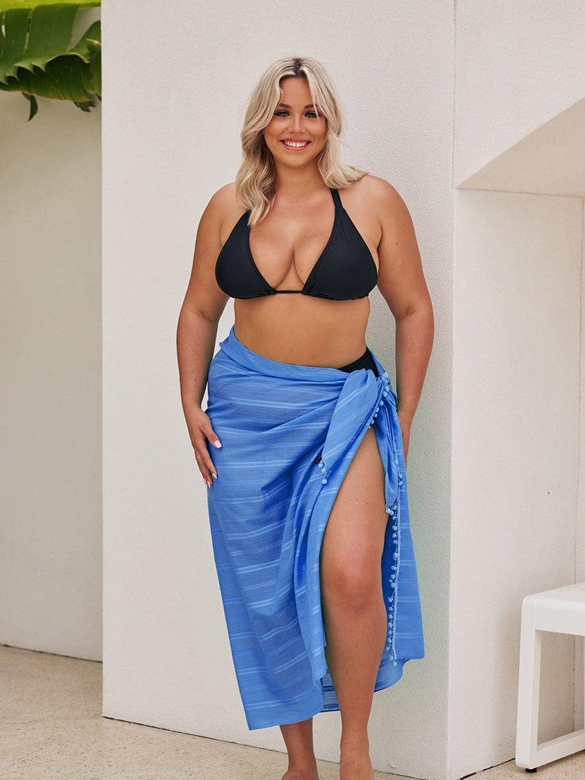 Blonde model wearing a side tie sarong with pom pom detail