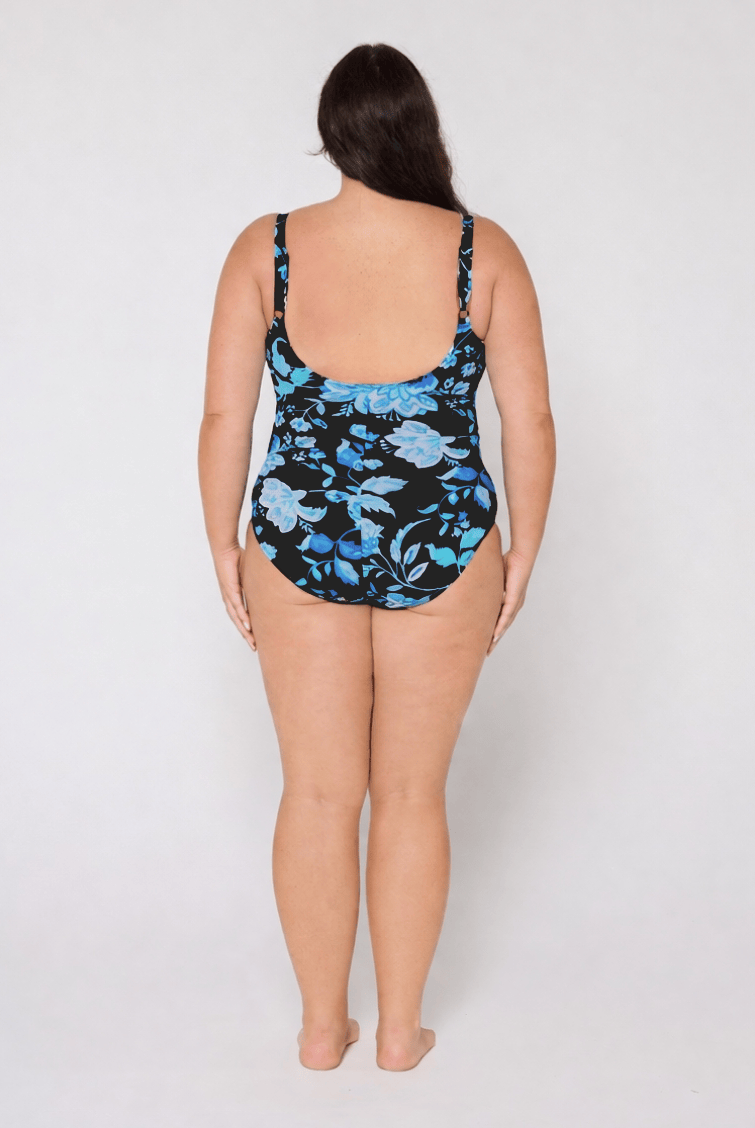 Woman wearing a blue and black floral swimsuit with scoop back